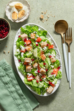 Mix salad in oval plate with eggs and pomegranate