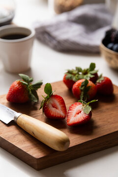 Fresh strawberries on kitchen counter sliced on a wooden board in soft morning light