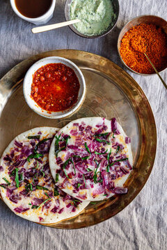 Onion uthappam served with spicy chutneys and curry leaf garnish