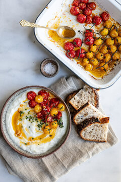 Roasted cherry tomatoes on vine served over creamy yogurt with herbs