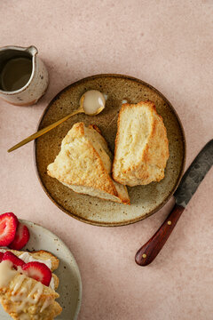 Flaky golden scones served on a rustic plate with strawberry scones on side