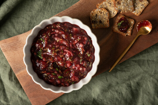Cranberry salsa served with crackers on a wooden board