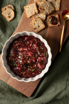 Cranberry salsa served with crackers on a wooden board