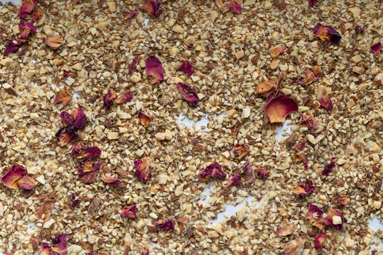 Dukkah spice blend with scattered dried rose petals on white background