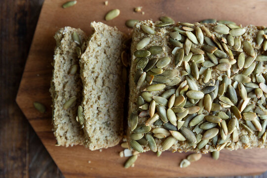 Brown rice pumpkin seed&ndash;topped loaf bread on cutting board