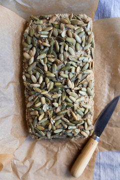 Brown rice pumpkin seed&ndash;topped loaf bread on parchment paper