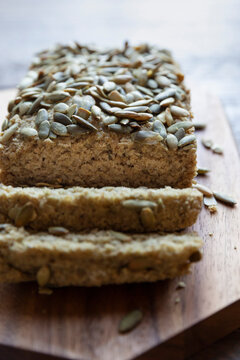 Brown rice pumpkin seed&ndash;topped loaf bread on cutting board
