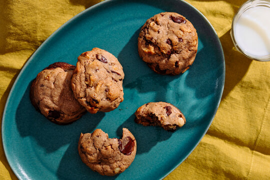 Chocolate chip cookies on teal plate with milk and yellow cloth