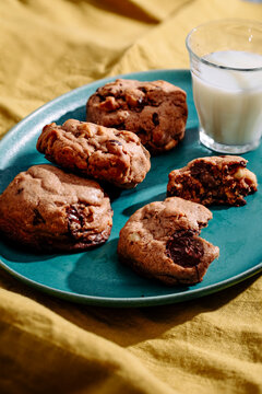 Chocolate chip cookies on teal plate with milk and yellow cloth