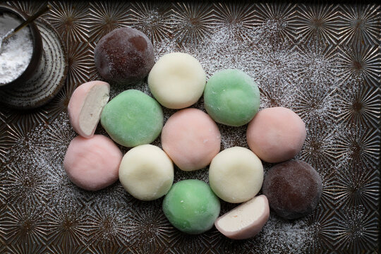 Assorted pastel mochi ice cream balls dusted with starch on a tray.