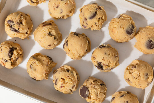 Chocolate chip cookie dough balls on white background on angled tray