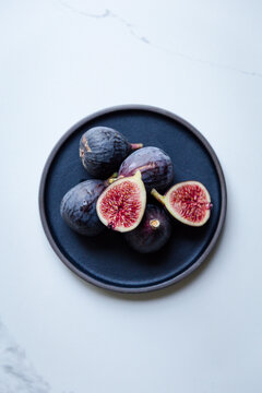 Fresh figs and a halved fig on a dark plate