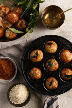 Kuzhi paniyaram in a cast-iron pan with spices