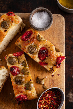 Sliced tomato and olive focaccia on a rustic wooden board