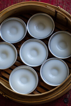 Steamed Chwee Kueh cakes in metal cups inside bamboo steamer