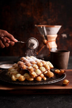 Egg waffles dusted with powdered sugar beside coffee setup