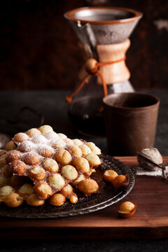 Egg waffles with powdered sugar beside coffee setup