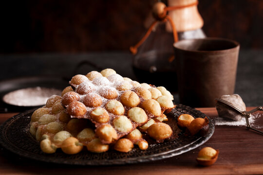 Egg waffles with powdered sugar beside coffee setup