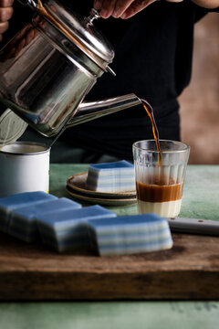 Blue-and-white kueh lapis sagu with kopi being poured