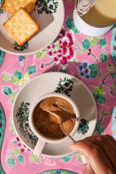 Kopi with condensed milk and crackers on a vibrant floral tray