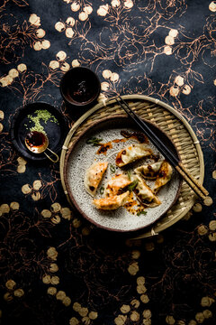 Steamed dumplings with chili oil on speckled plate and woven tray