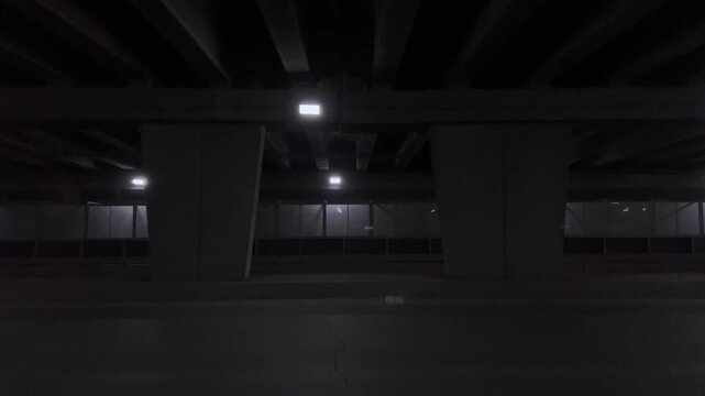 Illuminated urban underpass tunnel with concrete columns and road at night