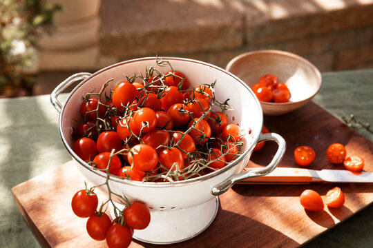 Fresh grape tomatoes on the vine in a colander outdoors