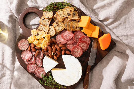 Charcuterie board with meats, cheeses, crackers, nuts and herbs