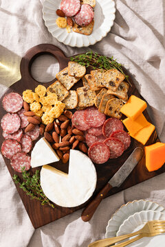 Charcuterie board with meats, cheeses, crackers, nuts and herbs