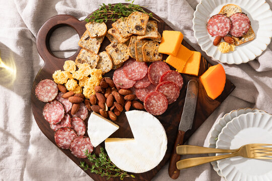 Charcuterie board with meats, cheeses, crackers, nuts and herbs