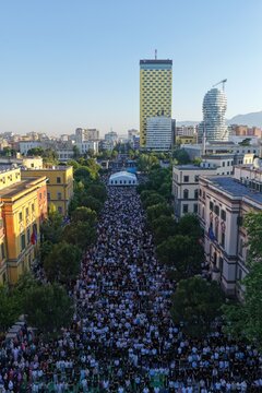 Tirana, Albania - 28 May 2026: Aerial view of a large crowd gathered for prayer in Skanderbeg Square with modern buildings and a yellow skyscraper under a clear sky.