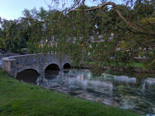 Naklejka premium The beautiful peaceful brick bridge cross the clean canal and riverside lush green trees