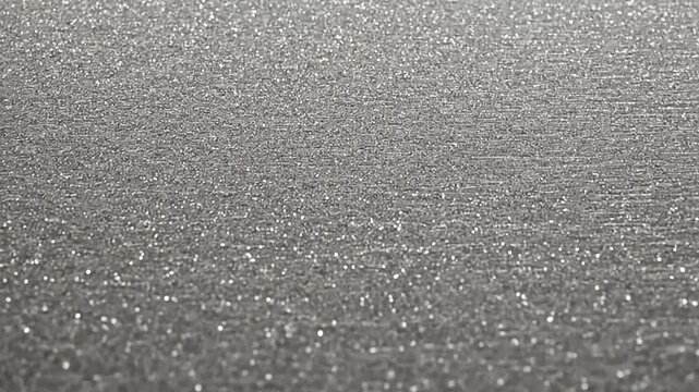 A close up view of a shimmering silver surface with many tiny sparkling light points