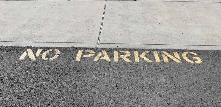 A close view of the yellow painted no parking sign.