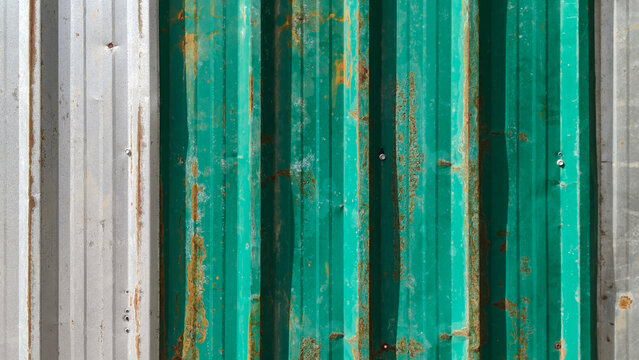 old Galvanized sheet with scratch and dented and dirty rusted screws. aged paint, and rough grunge detail, with shadow from leaves on galvanized sheet