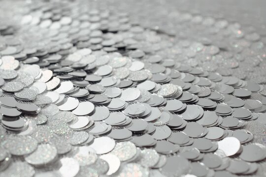 Close-up of metallic silver sequins on fabric creating a fish-scale inspired texture and shimmering reflections