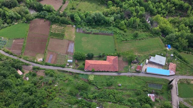 Aerial video featuring  a patchwork of farm fields, rural tracks, and houses in Katund i Vjeter within the Mirdita Region.