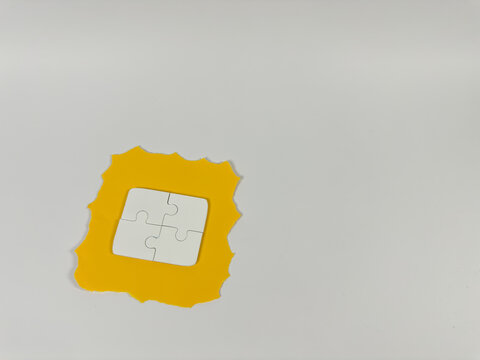 white puzzle pieces form a square over a yellow paper frame with jagged edges, conceptually representing completed solutions, successful teamwork, total security, comprehensive integration.