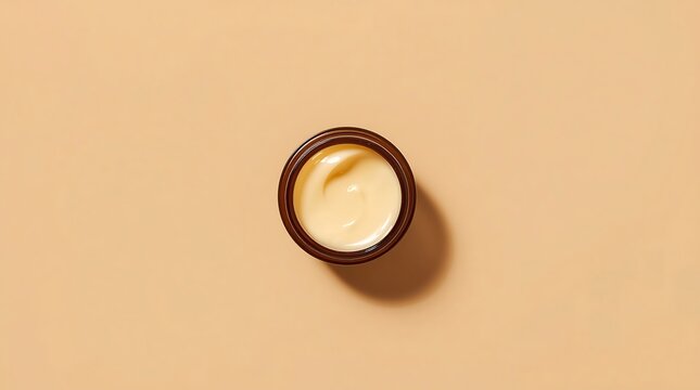 Top-Down View of a Small, Open Jar of Creamy Skincare Product on a Beige Surface.
