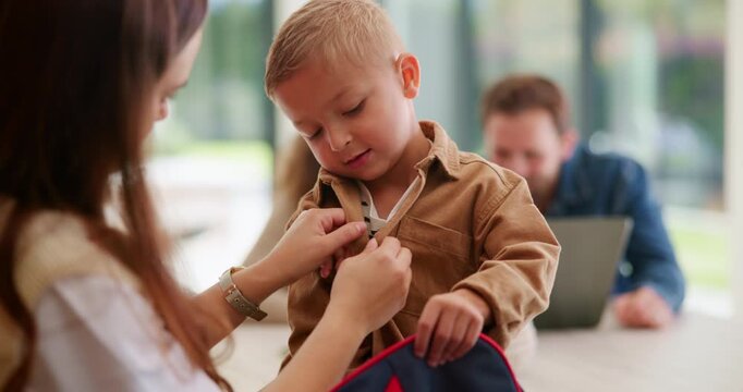 Dressing, help and mother with son in home for back to school, morning routine and support. Getting ready, love and kindergarten with woman and child packing backpack in kitchen of family house