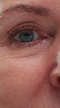 Vision old woman. Retirement portrait with eye of a senior person with wrinkles blinking closeup. Face of elderly female open eyes, looking at camera. Opening older view, skin texture. Head shot