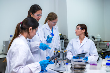 Fototapeta premium Team of professional scientists in lab coat researching and developing vaccine with high tech laboratory equipped for global pandemic outbreak in laboratory