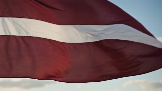 Latvian flag waving in sky