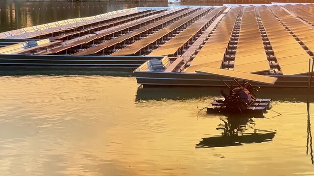 Floating solar panels and solar-powered water aerator on a lake during a golden sunset, renewable green energy footage