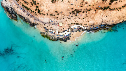 Landscape aerial drone shot of the blue lagoon beach and port in malta, comino island with green foliage and limestone rock and sandy beach busy with tourists in summer © STJMEDIA