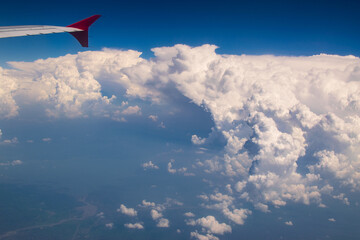 Fototapeta premium White clouds in sky with aeroplane wing. Image shot from flying aeroplane , cloudscape of India.