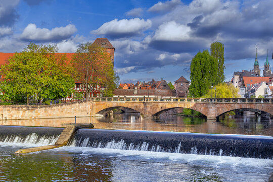 Close up view of historic Max Bridge with a water weir on Pegnitz river in Nuremberg, Germany. Stone architecture, day light