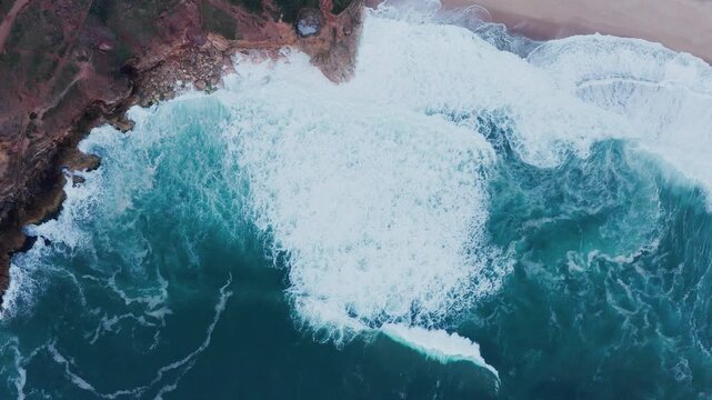 Aerial view of huge Atlantic ocean waves crushinf over cliffs on Praia do Norte in Nazare, Farol da Nazar&eacute;, Portugal where Guinness highest surfing World Recordwas was set. 4K drone top view.