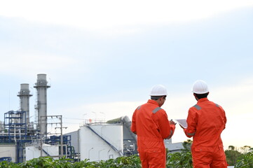 Fototapeta premium Industrial engineers inspecting operations at a petrochemical and energy plant. Professionals monitoring production systems, infrastructure, safety standards and industrial facility performance.