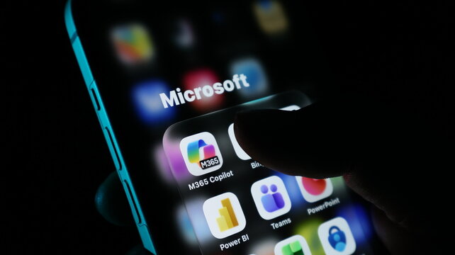 Closeup of a finger touching the microsoft 365 copilot app icon on a smartphone screen, showcasing various microsoft application icons